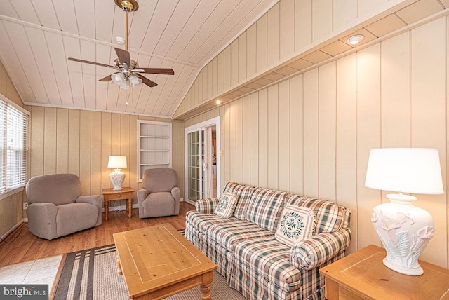 living room featuring hardwood / wood-style floors, wooden walls, and vaulted ceiling