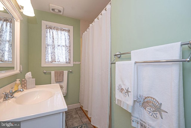 bathroom with tile patterned flooring, vanity, and a healthy amount of sunlight