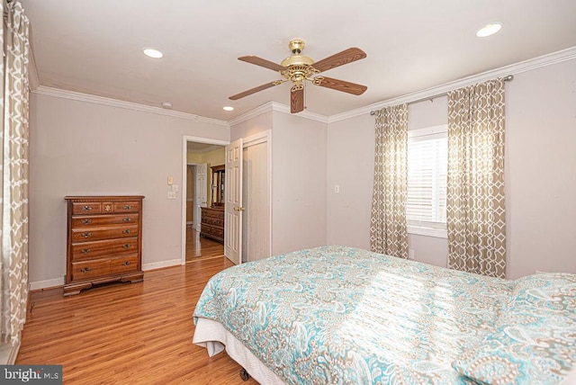 bedroom featuring a closet, light hardwood / wood-style floors, ceiling fan, and crown molding