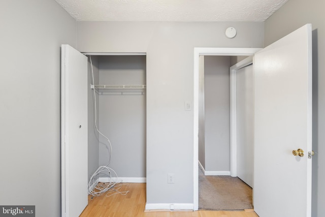 unfurnished bedroom with hardwood / wood-style flooring, a closet, and a textured ceiling