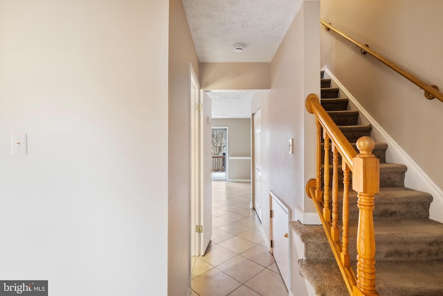 staircase with tile patterned floors and a textured ceiling