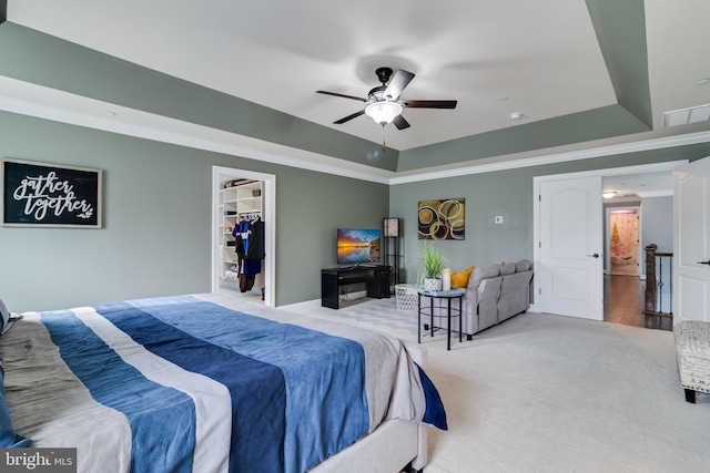 bedroom with ornamental molding, a raised ceiling, light carpet, and a spacious closet