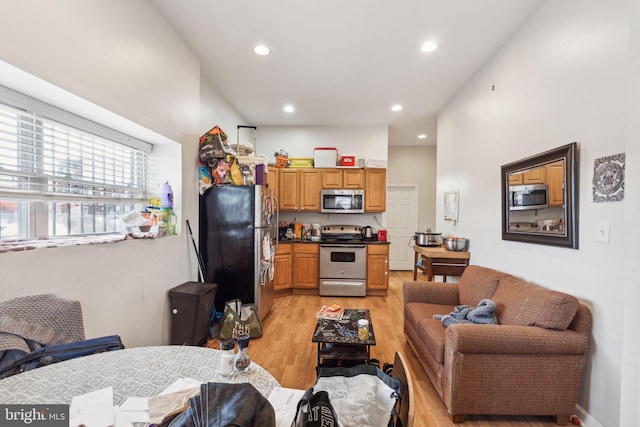 kitchen featuring a high ceiling, light wood-type flooring, and stainless steel appliances