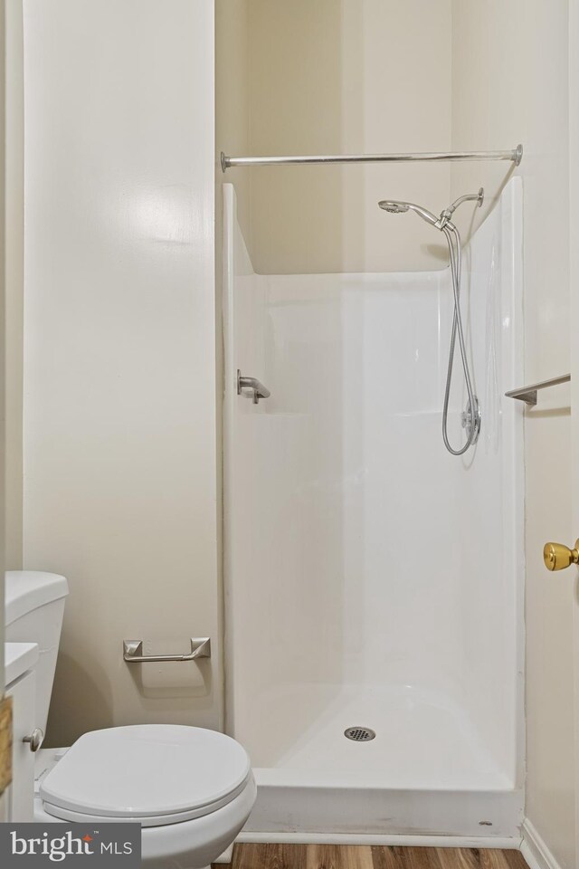 bathroom featuring a shower, hardwood / wood-style flooring, and toilet