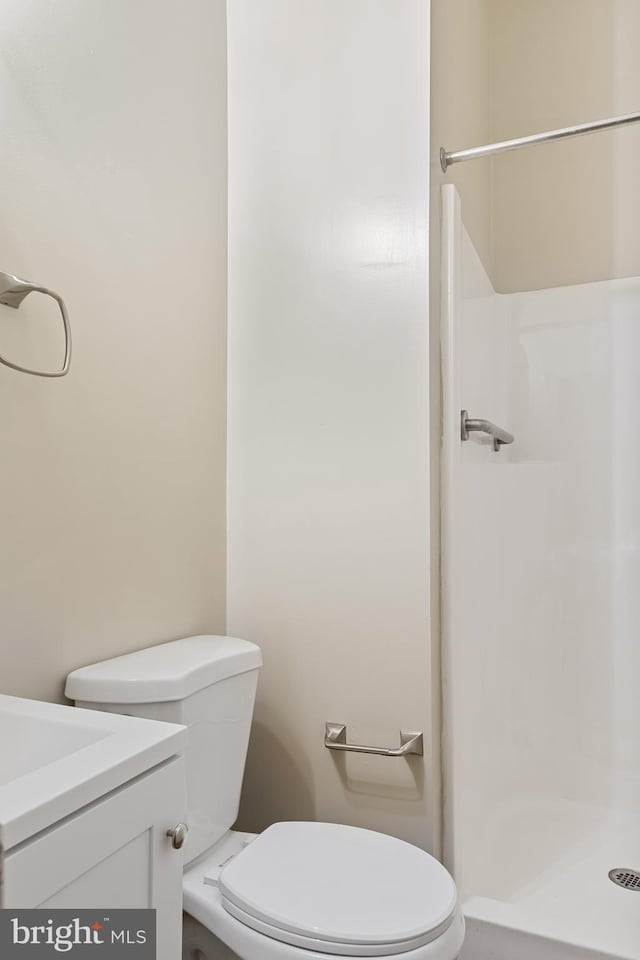 bathroom featuring a shower, vanity, and toilet