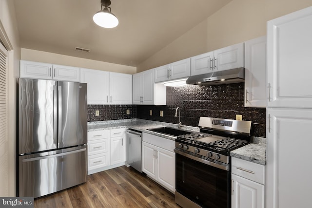 kitchen with stainless steel appliances, vaulted ceiling, white cabinetry, and dark wood-type flooring