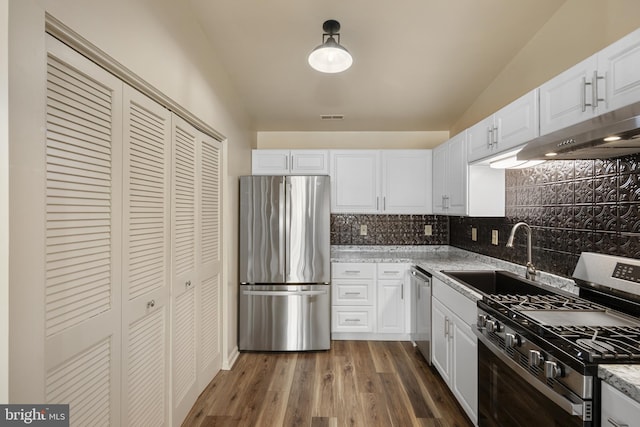 kitchen featuring white cabinets, dark hardwood / wood-style floors, decorative backsplash, light stone countertops, and stainless steel appliances