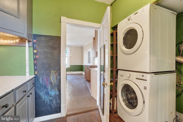 laundry area with wood-type flooring and stacked washer and dryer