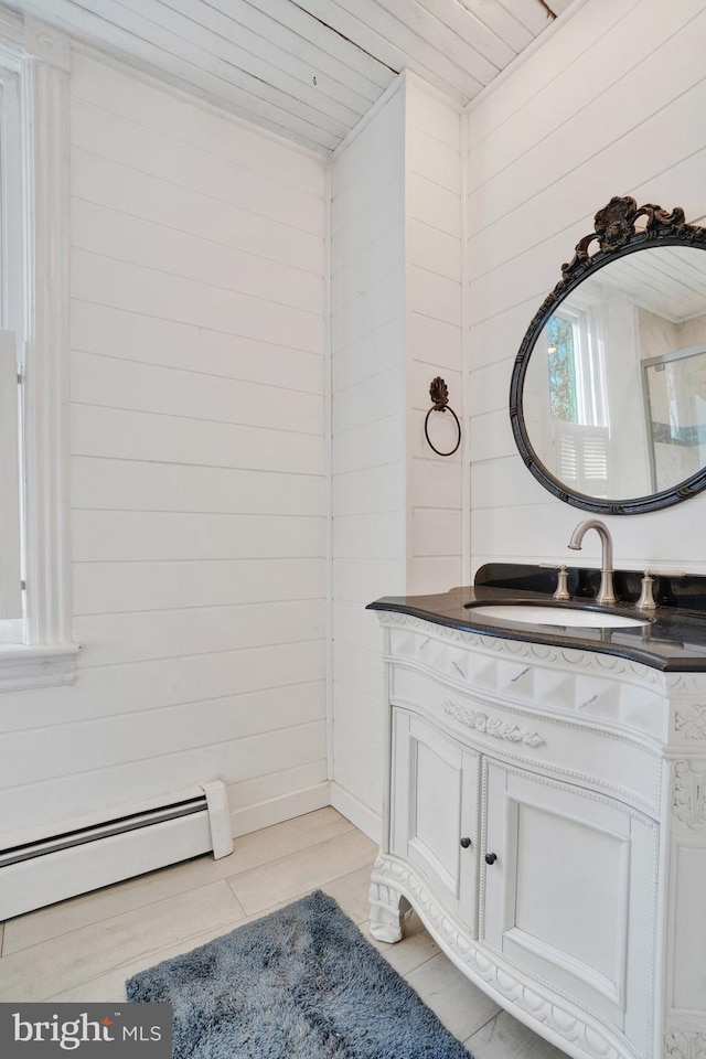 bathroom featuring a baseboard heating unit, vanity, wooden ceiling, and wooden walls