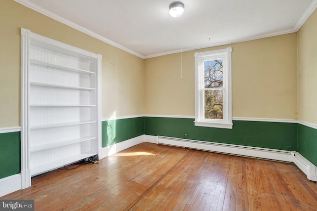 spare room with crown molding, built in features, wood-type flooring, and a baseboard heating unit