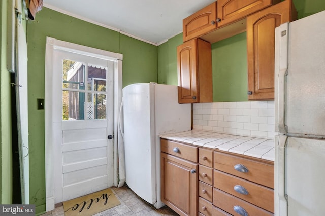 kitchen featuring tile countertops, backsplash, and white fridge