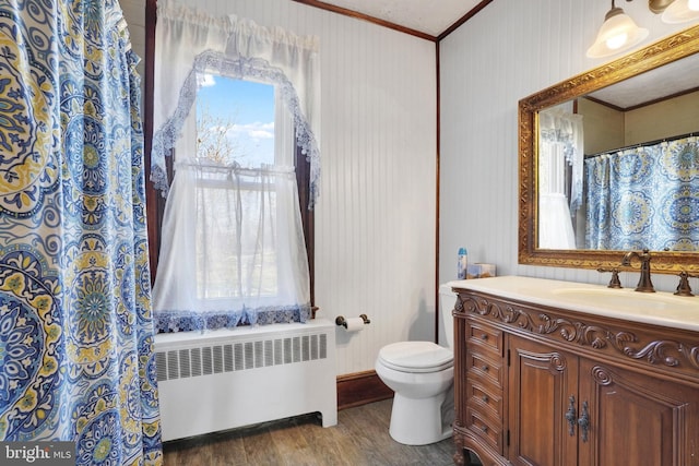 bathroom featuring vanity, crown molding, wood-type flooring, radiator heating unit, and toilet