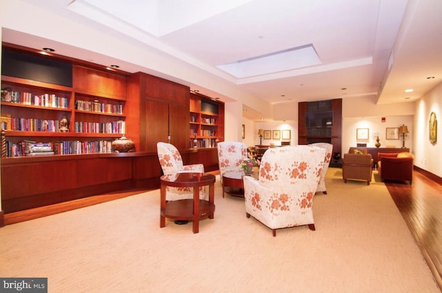 living area with a tray ceiling and light hardwood / wood-style flooring