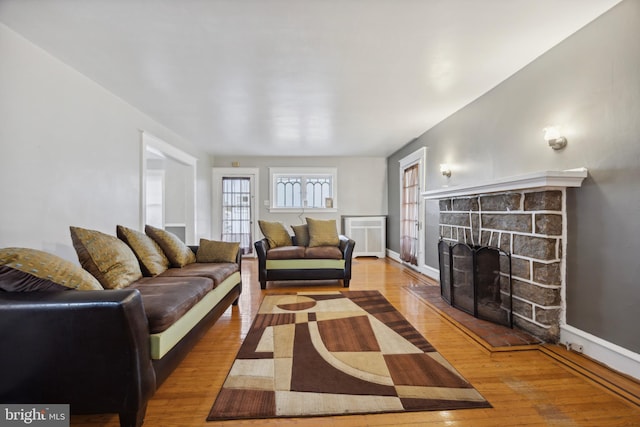 living room with wood-type flooring and a stone fireplace