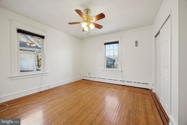 unfurnished bedroom featuring a closet, ceiling fan, hardwood / wood-style floors, and a baseboard radiator