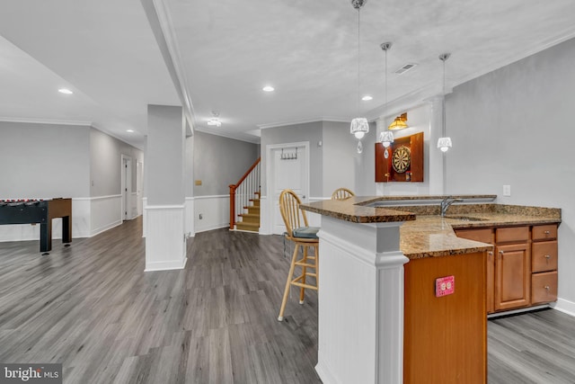 7238 Farr St, Annandale, VA 22003 - kitchen with a sink, crown molding, a breakfast bar area, stone countertops, and wood finished floors