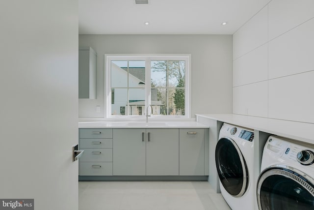 washroom with cabinets, separate washer and dryer, and sink