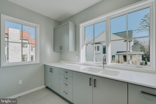 kitchen featuring gray cabinetry, a wealth of natural light, sink, and light tile patterned flooring