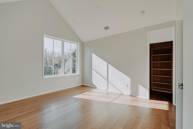 unfurnished room with light wood-type flooring and high vaulted ceiling