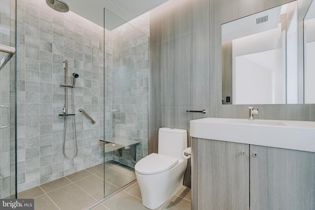 bathroom featuring toilet, a tile shower, vanity, and tile patterned floors