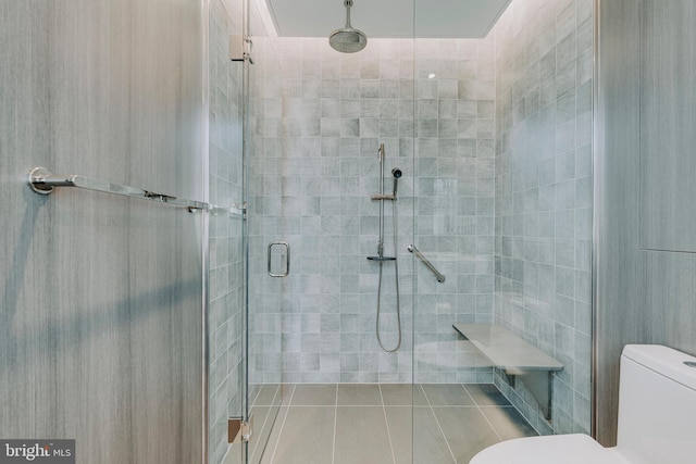 bathroom featuring tile patterned floors, a shower with shower door, and toilet