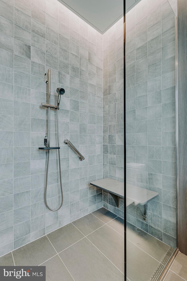 bathroom with tile patterned flooring and a tile shower