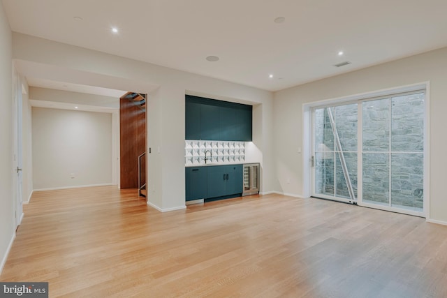 unfurnished living room with wine cooler and light hardwood / wood-style flooring