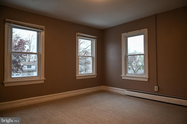 carpeted spare room featuring a healthy amount of sunlight and baseboard heating