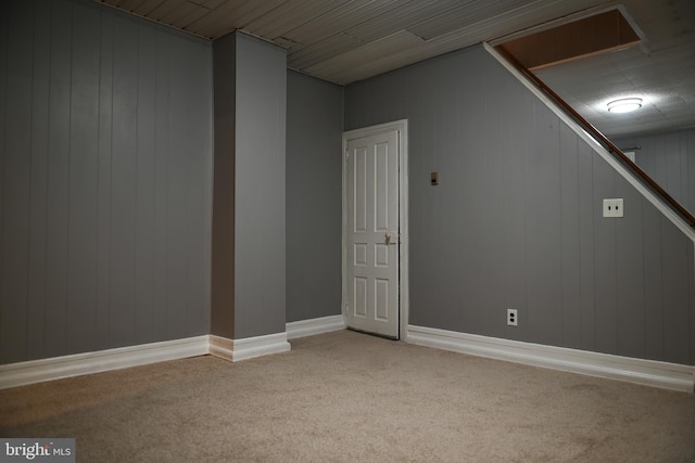 basement featuring light carpet and wooden walls