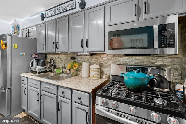 kitchen with sink, decorative backsplash, gray cabinets, appliances with stainless steel finishes, and dark hardwood / wood-style flooring