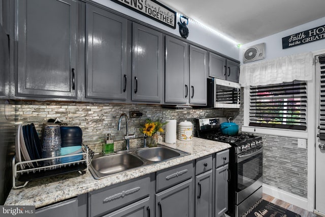 kitchen with sink, hardwood / wood-style flooring, decorative backsplash, gray cabinets, and stainless steel appliances