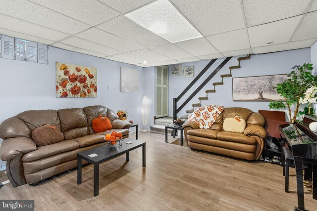 living room with a drop ceiling and light wood-type flooring