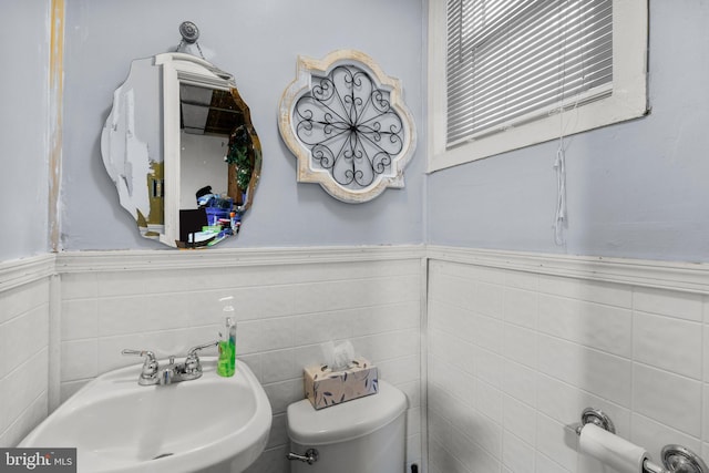 bathroom with toilet, tile walls, and sink