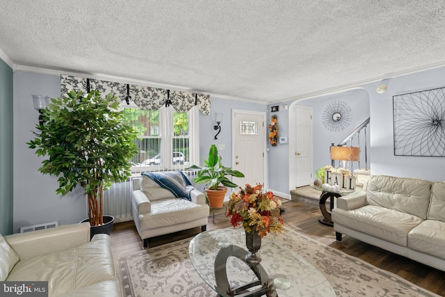 living room featuring ornamental molding, a textured ceiling, and hardwood / wood-style flooring