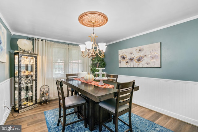 dining space featuring crown molding, hardwood / wood-style floors, and a notable chandelier