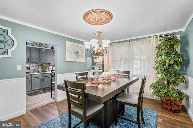 dining area with an inviting chandelier, dark wood-type flooring, and ornamental molding