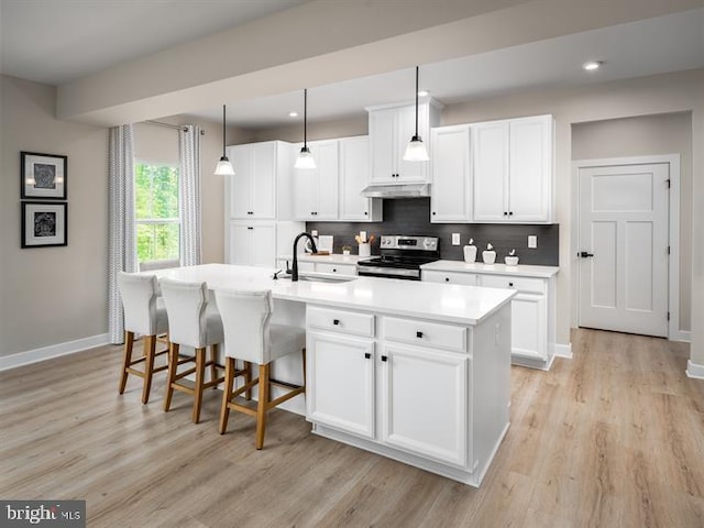 kitchen featuring stainless steel range with electric stovetop, pendant lighting, a kitchen island with sink, white cabinets, and sink