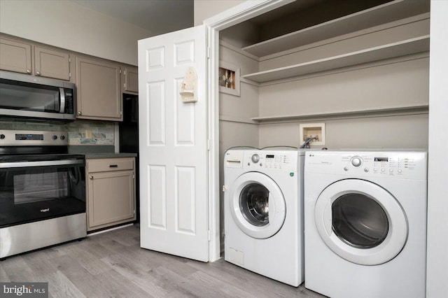 washroom with washing machine and dryer and light wood-type flooring