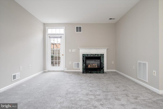 unfurnished living room featuring light carpet and a high end fireplace