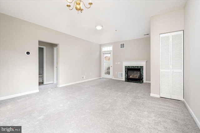 unfurnished living room with a chandelier, light carpet, and a premium fireplace