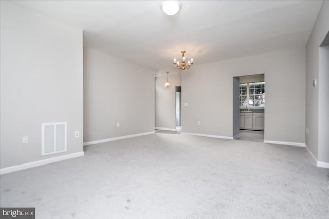 carpeted spare room with a notable chandelier