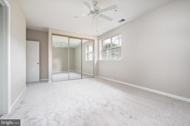 unfurnished bedroom featuring ceiling fan, a closet, and light colored carpet