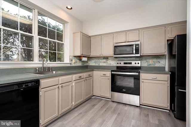 kitchen featuring decorative backsplash, sink, black appliances, and light hardwood / wood-style floors