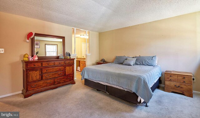 bedroom featuring a textured ceiling, light colored carpet, and connected bathroom