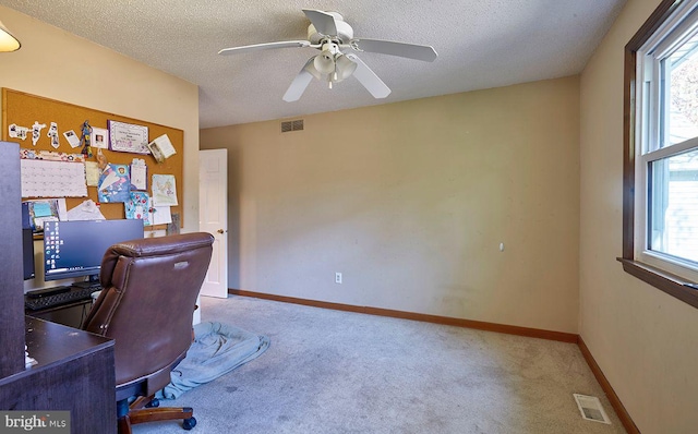 home office featuring carpet, ceiling fan, and a textured ceiling