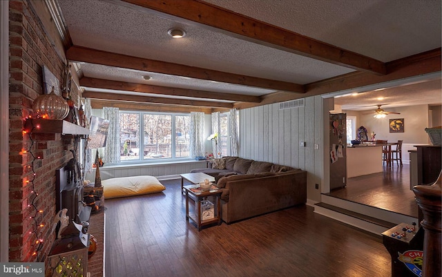 living room featuring ceiling fan, dark wood-type flooring, a textured ceiling, and a brick fireplace