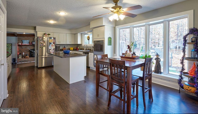 kitchen with a center island, dark hardwood / wood-style floors, a textured ceiling, white cabinets, and appliances with stainless steel finishes