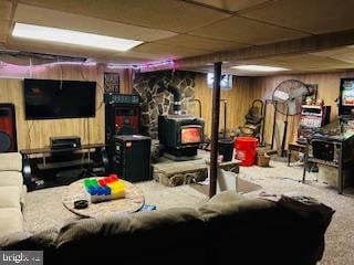 interior space with a wood stove, wooden walls, and carpet