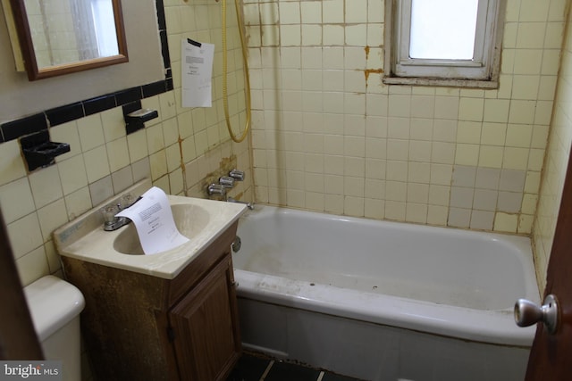 bathroom featuring vanity, toilet, and tile walls