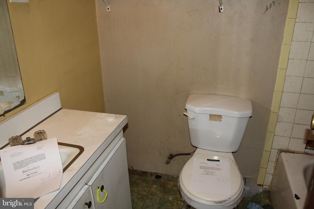 bathroom with a tub to relax in, vanity, and toilet